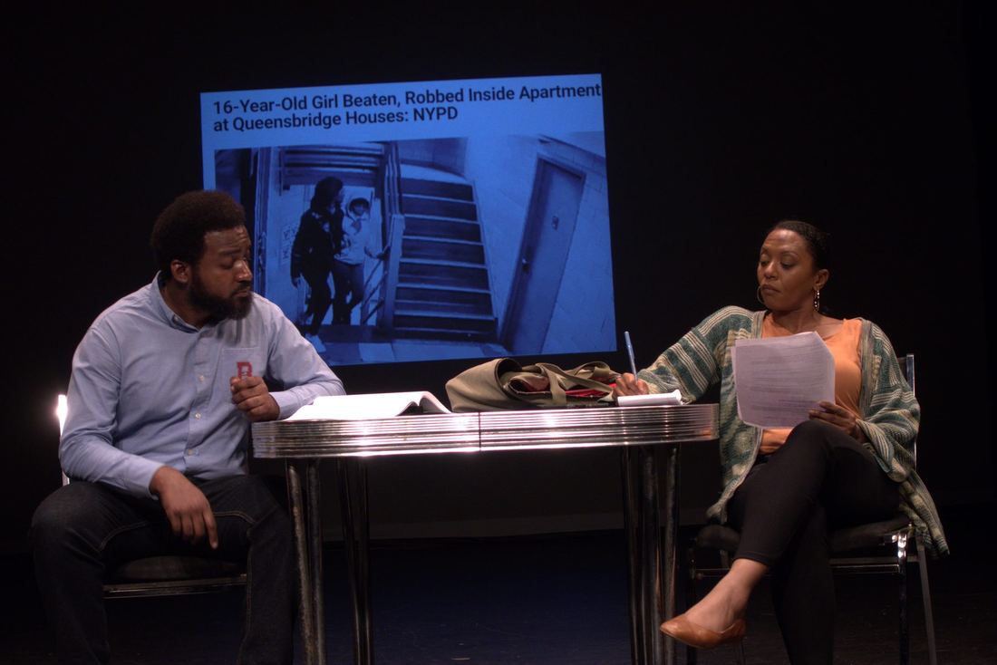 Two actors at a table during the staged interview