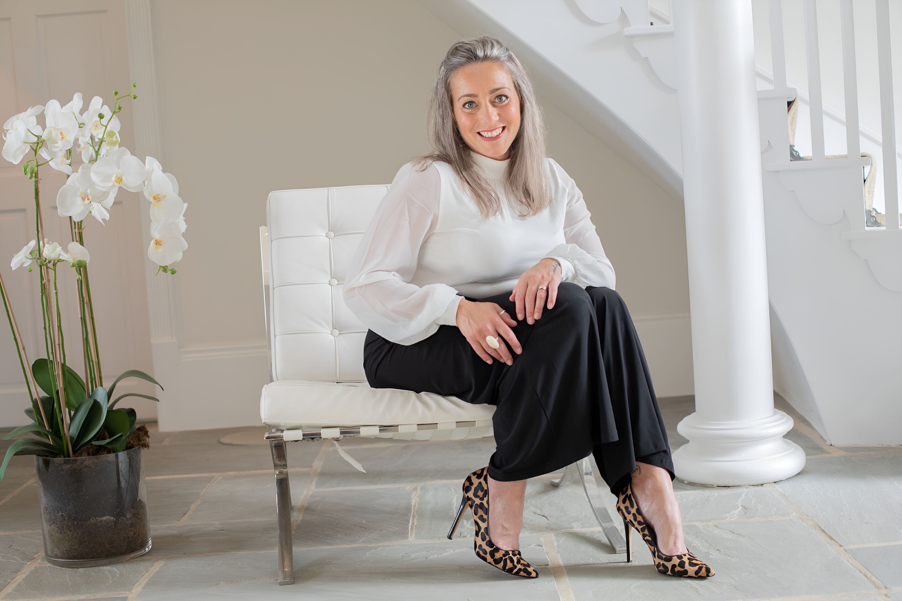 Lee-ann Cordingley in a white chair, laughing, leopard heels