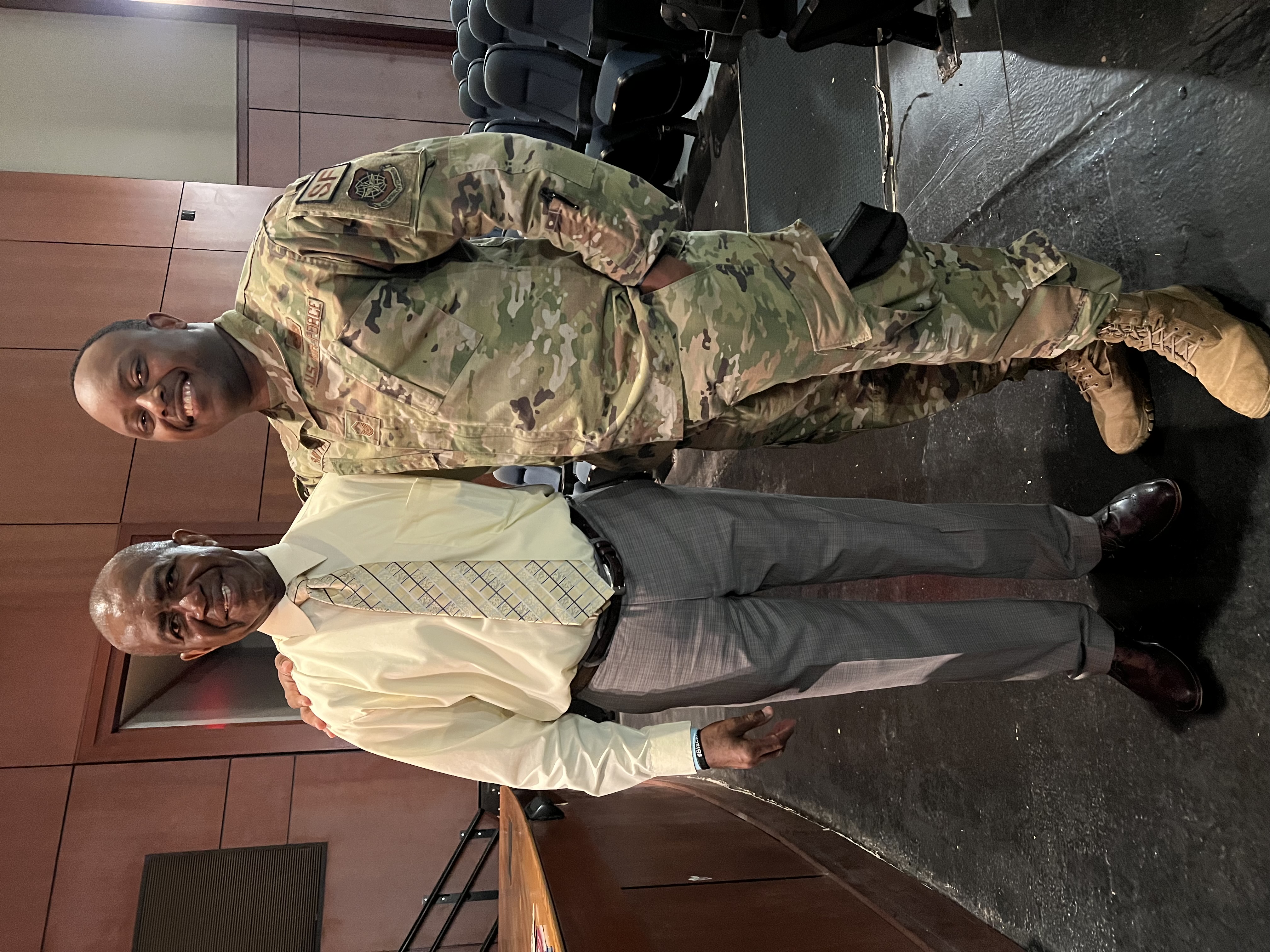 Lee Moultrie standing beside a United States Air Force service member in an auditorium