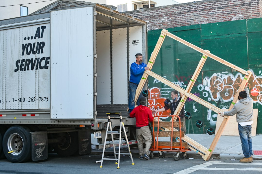 Junk removal crew in Toronto maneuvering a large wooden frame onto a transport box truck.