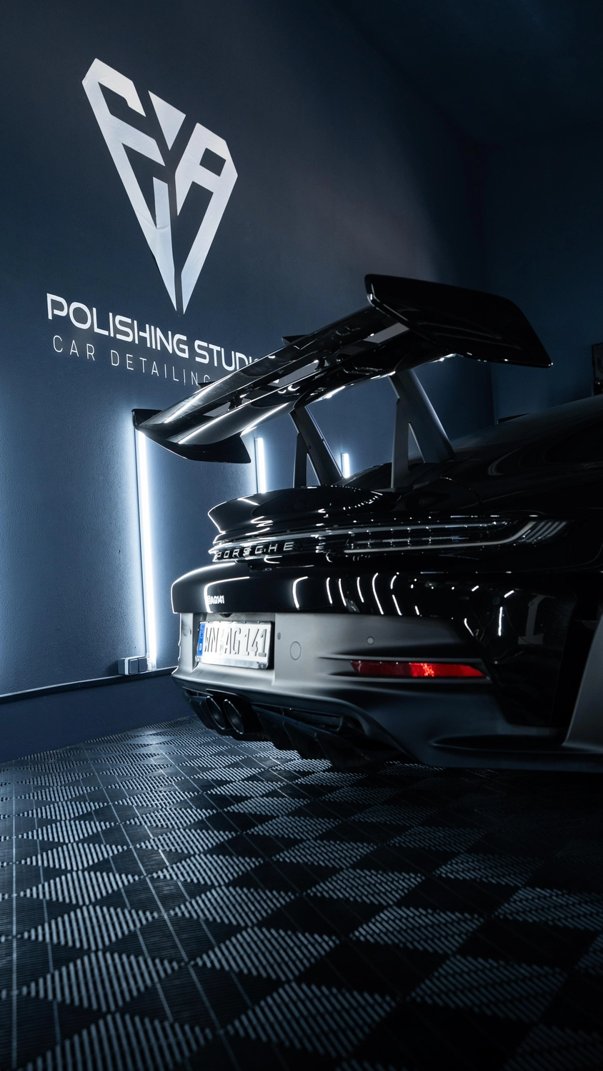 Porsche mit Heckflügel im Studio, Logo an der Wand