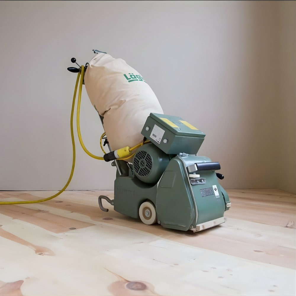 Professional hardwood floor sanding machine on newly installed wood flooring, showcasing the refinishing process for enhancing floor appearance and durability.