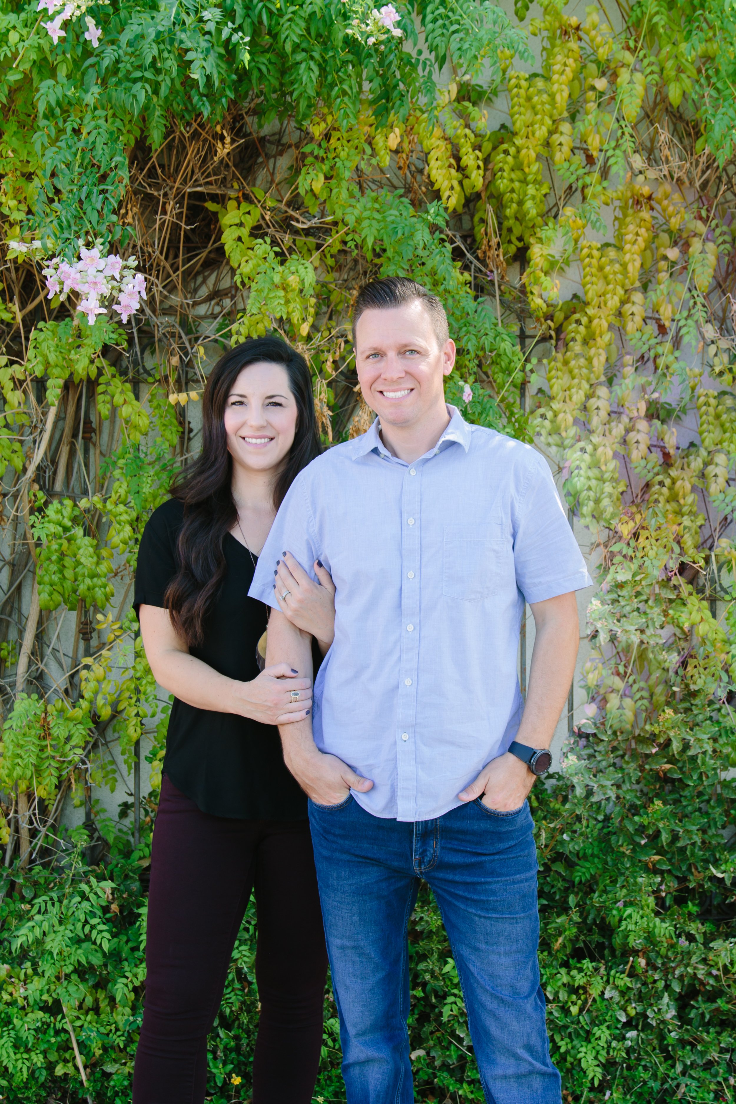 Ryan and Jenna Norris, founders of AZ Floor Haven, standing together outdoors against a backdrop of green foliage and flowers, showcasing their commitment to flooring services in Southern Arizona.