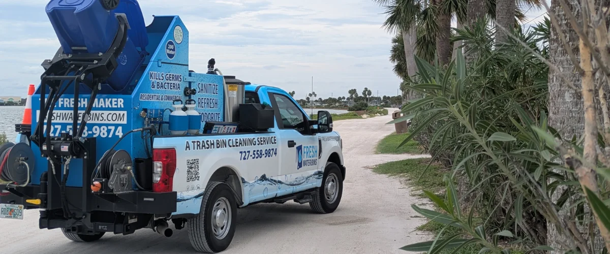 Two men in blue shirts and sunglasses giving peace signs beside a 'Trash Bin Cleaning Service' truck and blue bins. Two men in blue shirts and sunglasses giving peace signs beside a 'Trash Bin Cleaning Service' truck and blue bins.
