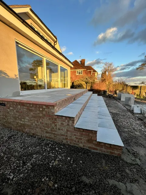 Patio steps with brick risers beside large glazed doors
