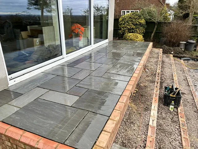 Paved patio with a brick edge outside sliding doors