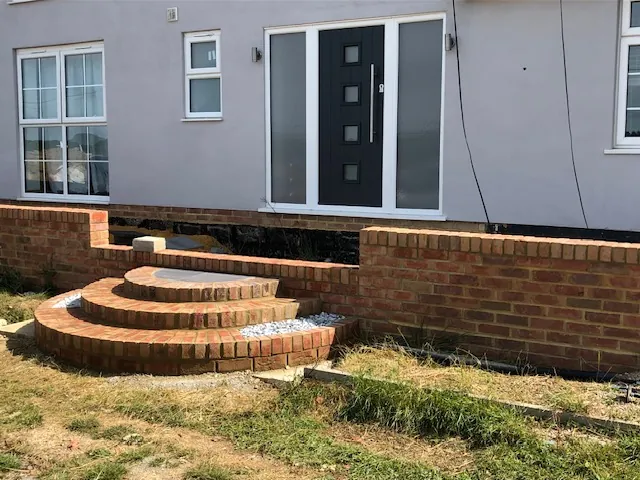 Curved brick steps and a low brick wall at the front of a house