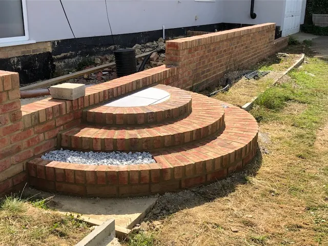 Curved brick steps beside a new brick garden wall