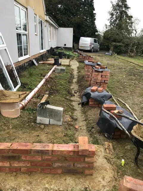 Brick garden walls being built along a house