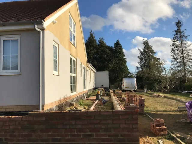 New brick garden wall along a rendered house