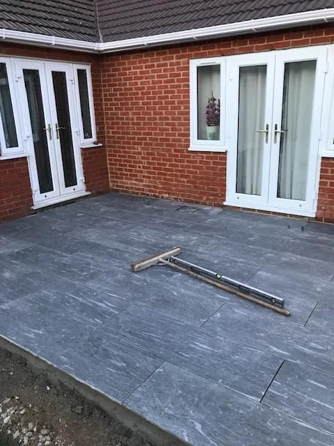Paved patio outside French doors at the back of a bungalow