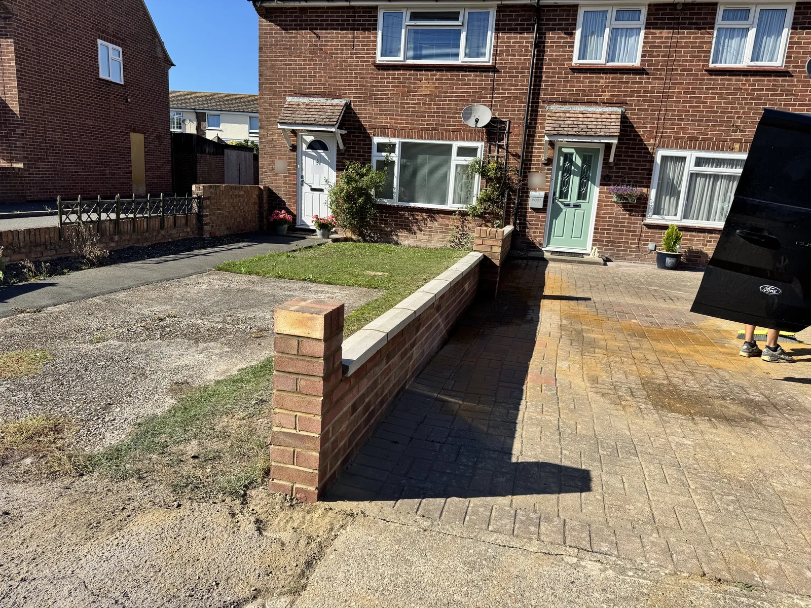 Low brick wall with a pier beside a block-paved driveway