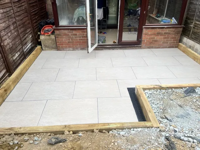 Pale paved patio framed with timber sleepers outside glazed doors