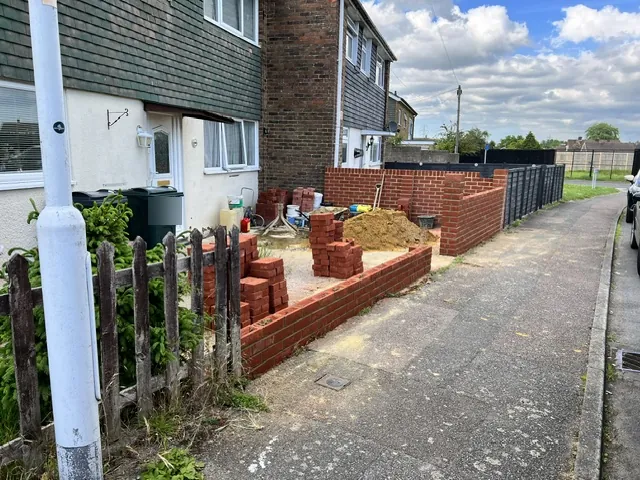 New red-brick front garden walls along a pavement