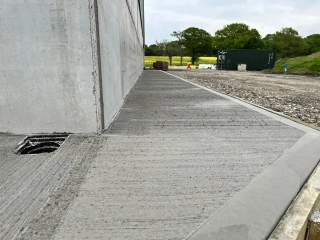 Brushed concrete path along the wall of a steel-framed building