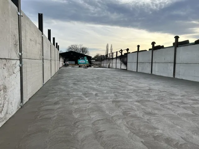 Freshly poured concrete yard between precast concrete walls