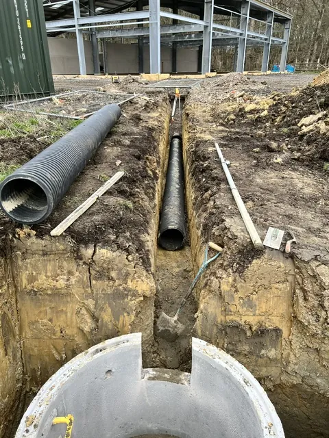Drainage pipe in a trench running into a concrete chamber ring