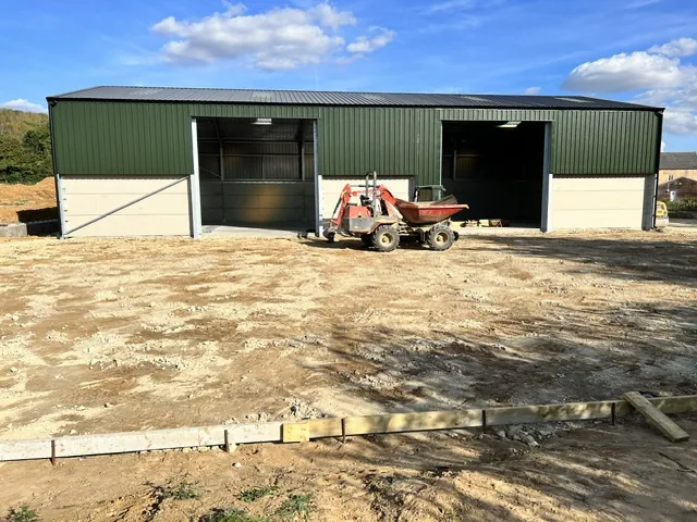 Levelled yard base with formwork in front of a steel barn