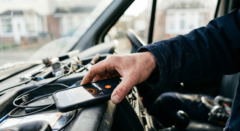 Close-up of a plumber's hand picking up a mobile phone within seconds of it ringing, blurred van interior in the background Close-up of a plumber's hand picking up a mobile phone within seconds of it ringing, blurred van interior in the background