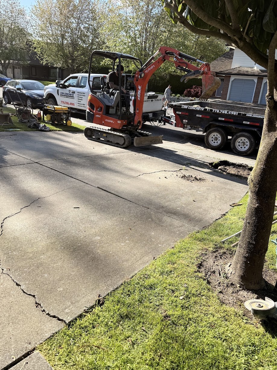 Mini excavator breaking out an old cracked concrete driveway during removal in Steveston, Richmond BC