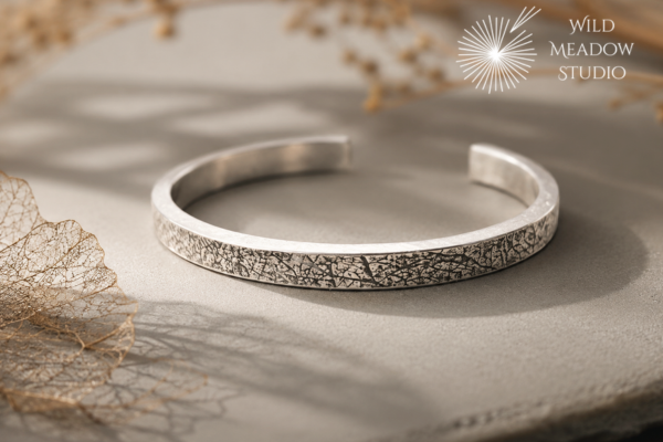 Handcrafted sterling silver cuff created from reclaimed family silver. The surface bears the delicate imprint of preserved leaf skeletons collected over twenty years ago, transforming cherished memories into a contemporary heirloom.