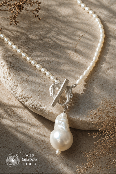 Luxury handmade freshwater pearl necklace featuring a handcrafted fine silver freeform T-bar clasp inspired by ocean waves and a large baroque pearl pendant. Bespoke commission by Wild Meadow Studio