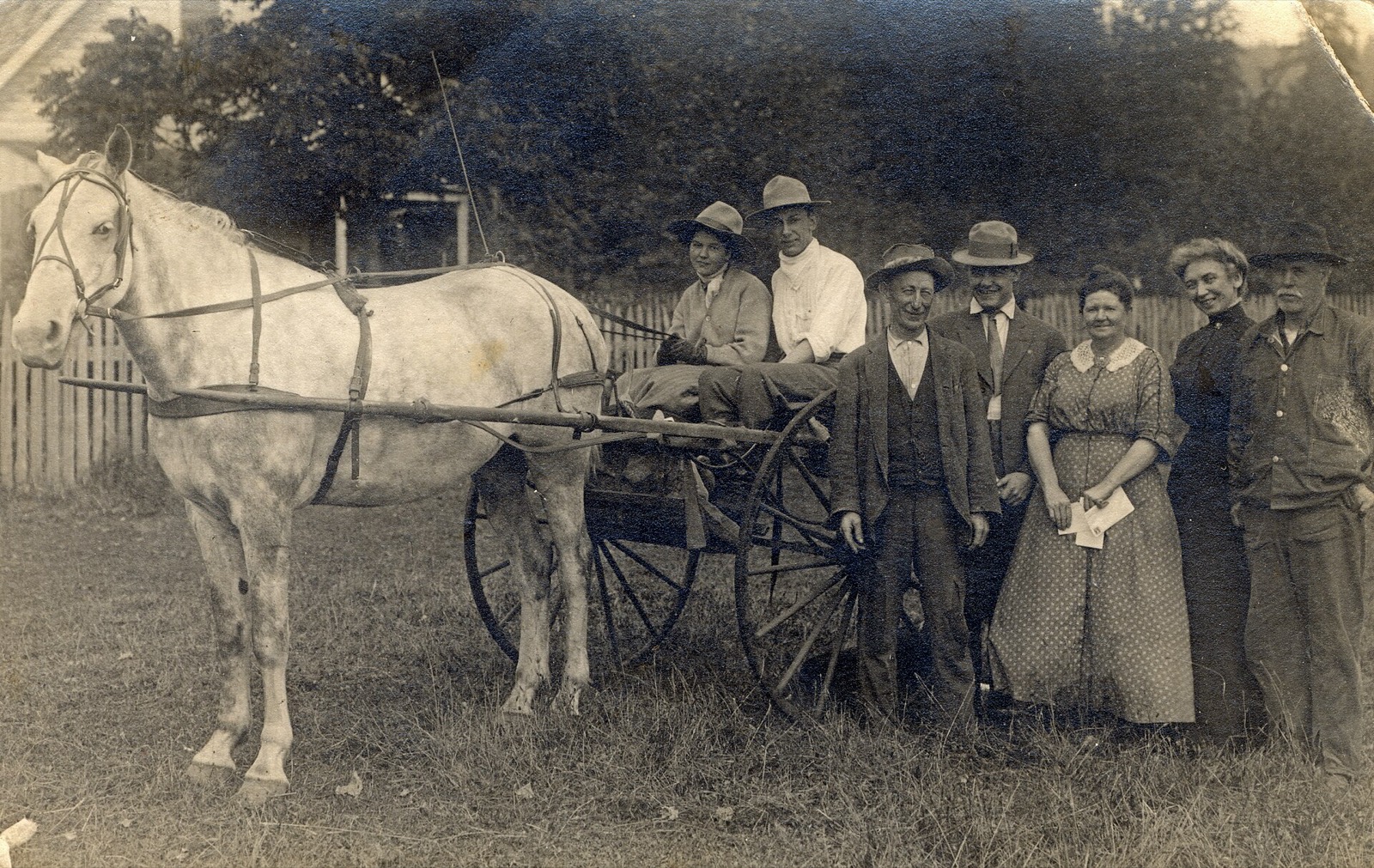 An early 1900s rural mail carrier in his cart with the families from along his route, one woman holding letters