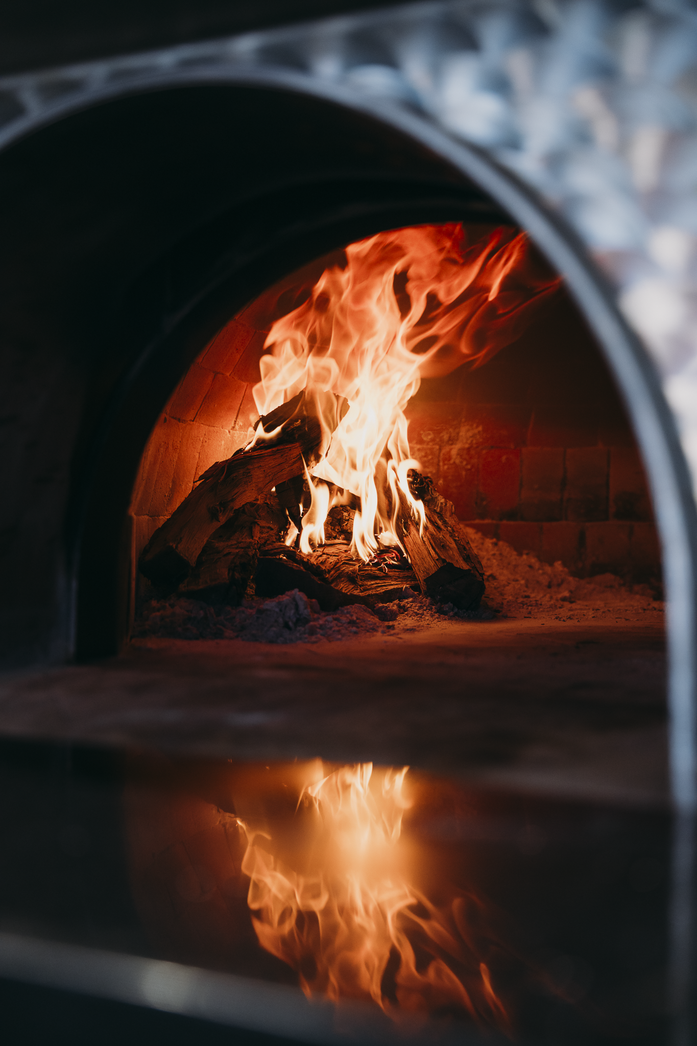 Wood-fired oven with burning flames showcasing Double E Lifestyle's culinary experiences in Texas.