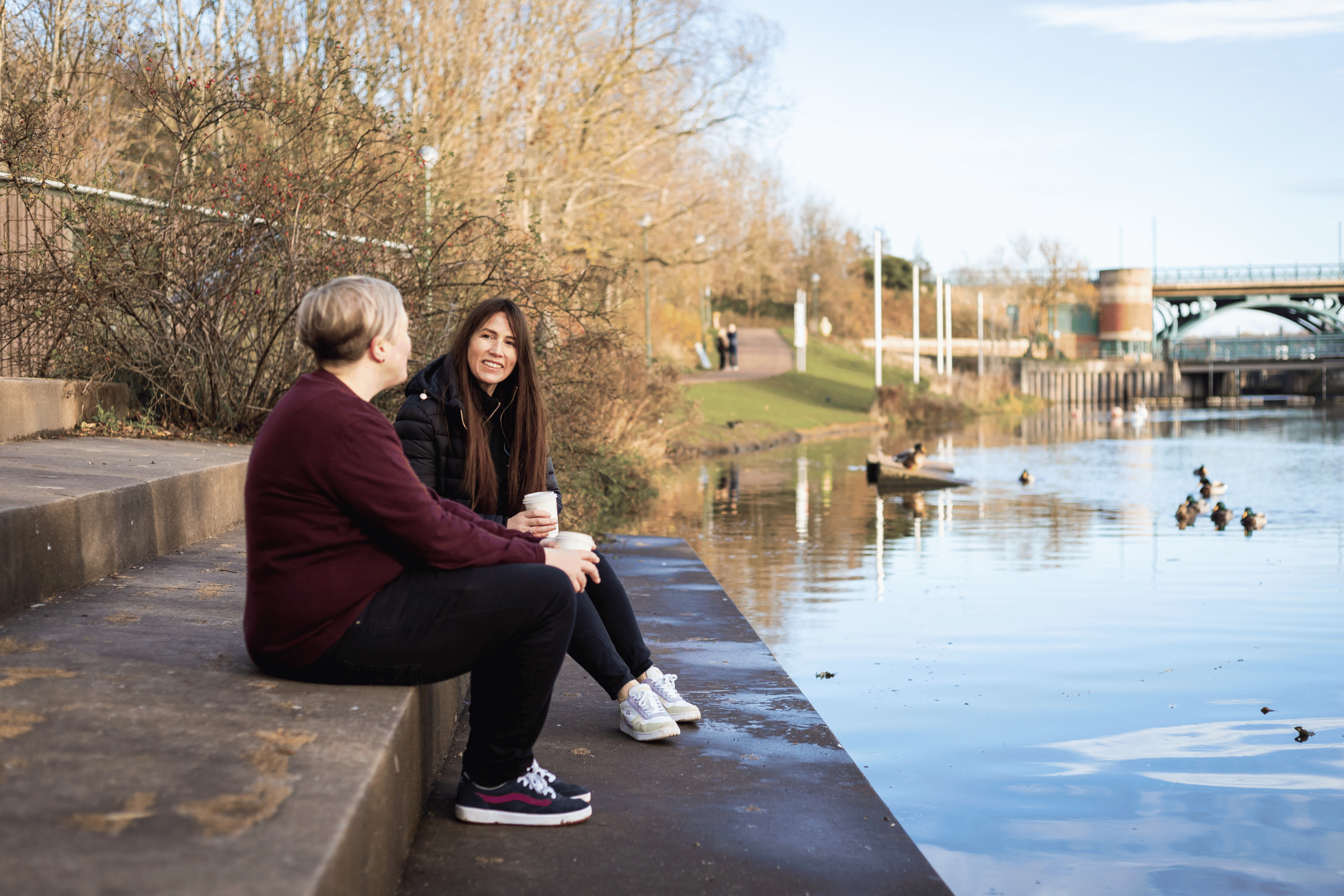two people talking sat by the river