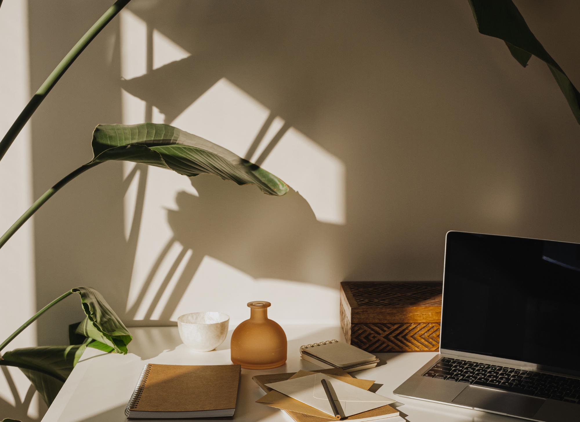 a sunsoaked desk with a journal and laptop, imperfect and messy