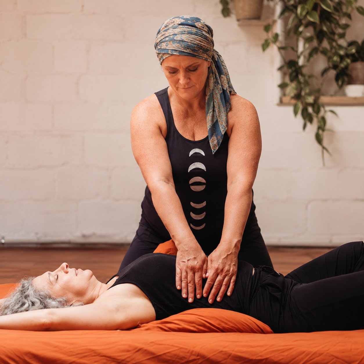 Mary kneeling on the mat, hands on a client’s abdomen