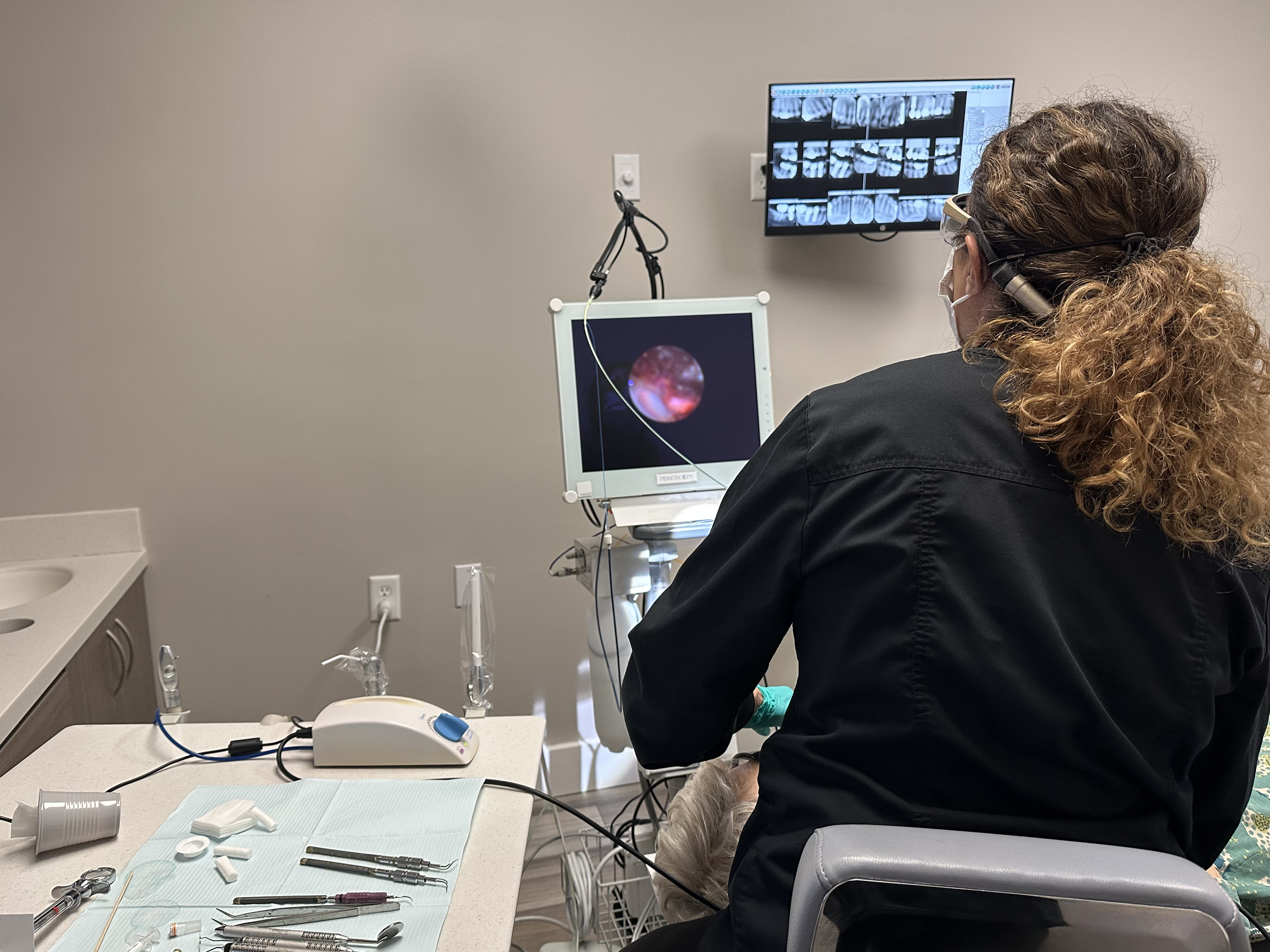 Rita Goddard performing perioscope-assisted therapy chairside, viewing the root surface on the perioscopy monitor