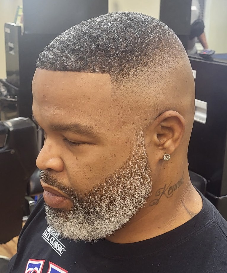 Bald fade with a crisp line-up and a groomed salt-and-pepper beard