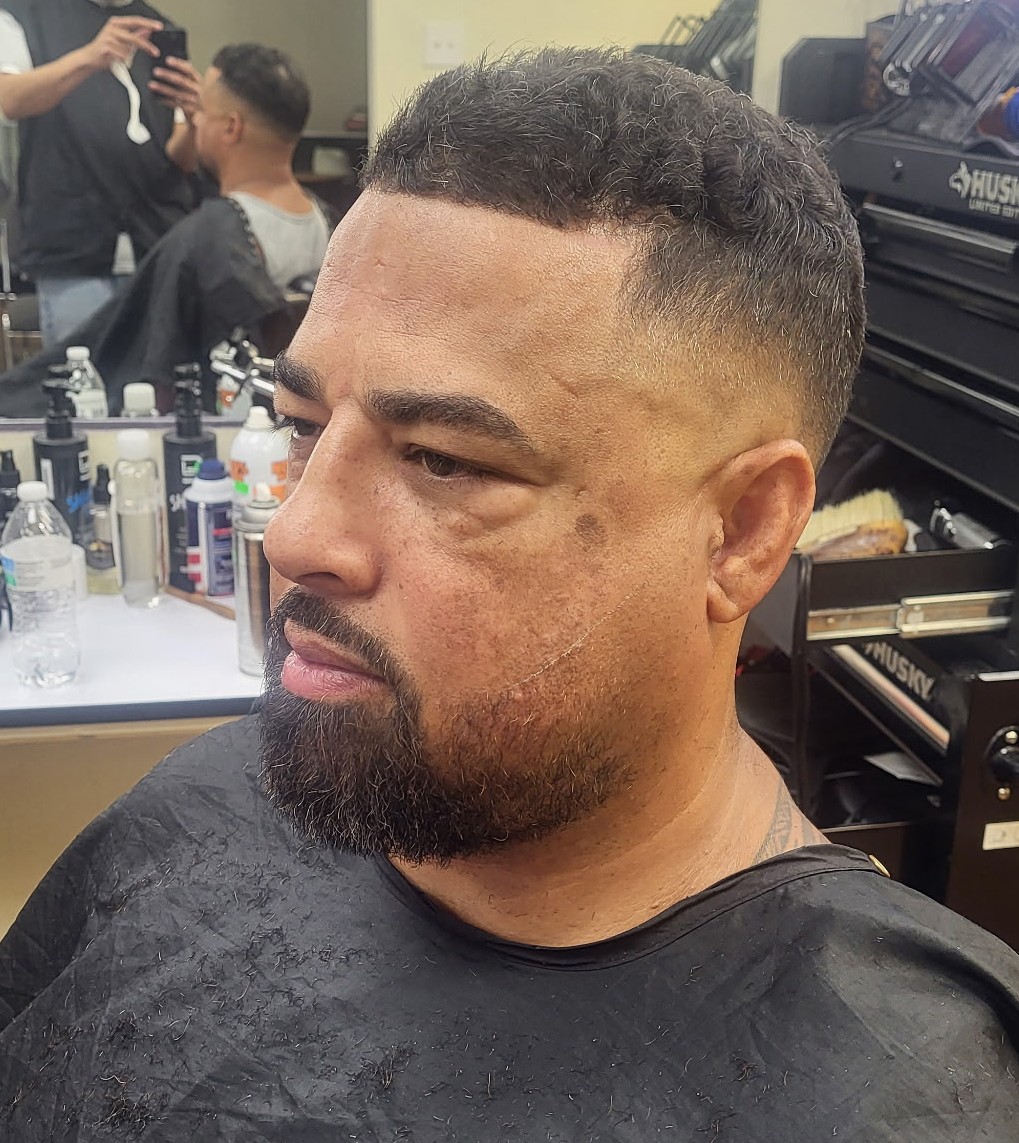 Skin fade with a sharp line-up and a full, shaped beard