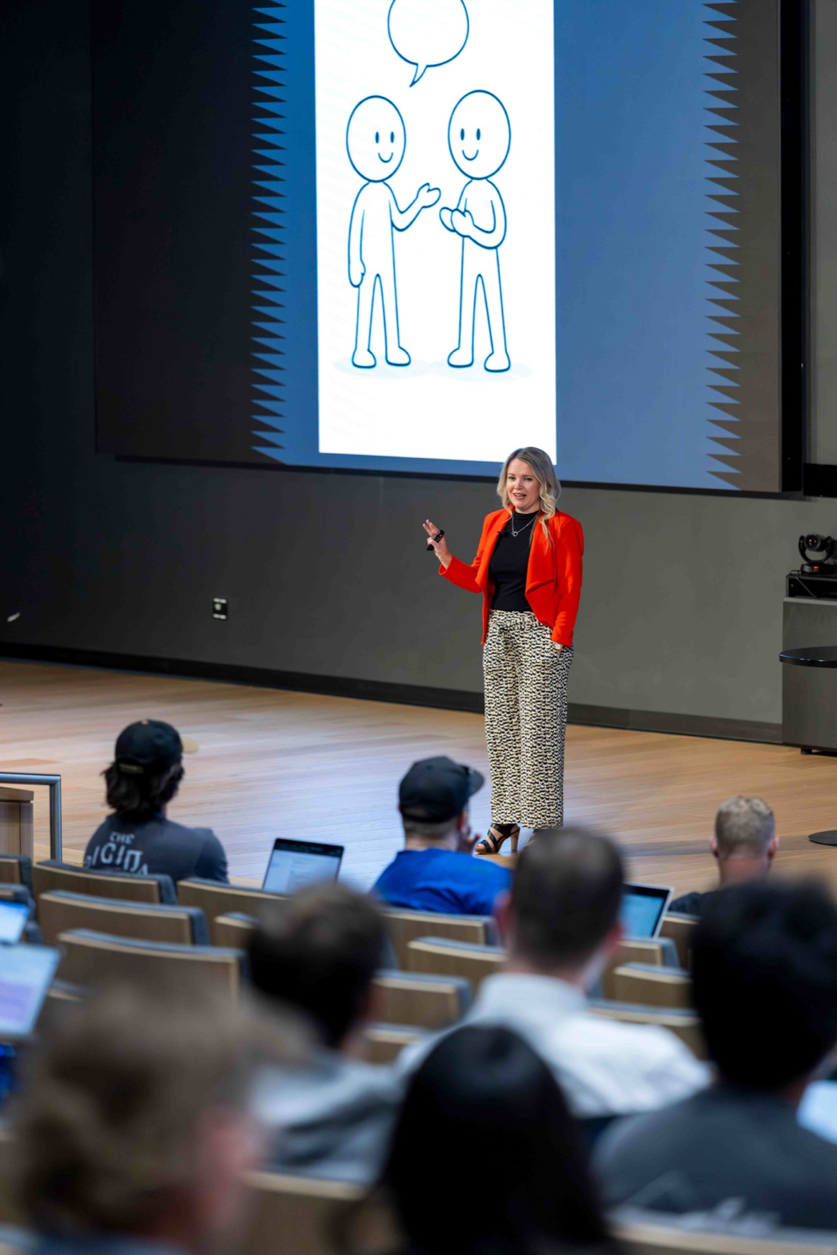 Ashlee Stratton in a red jacket teaching student leaders in an auditorium