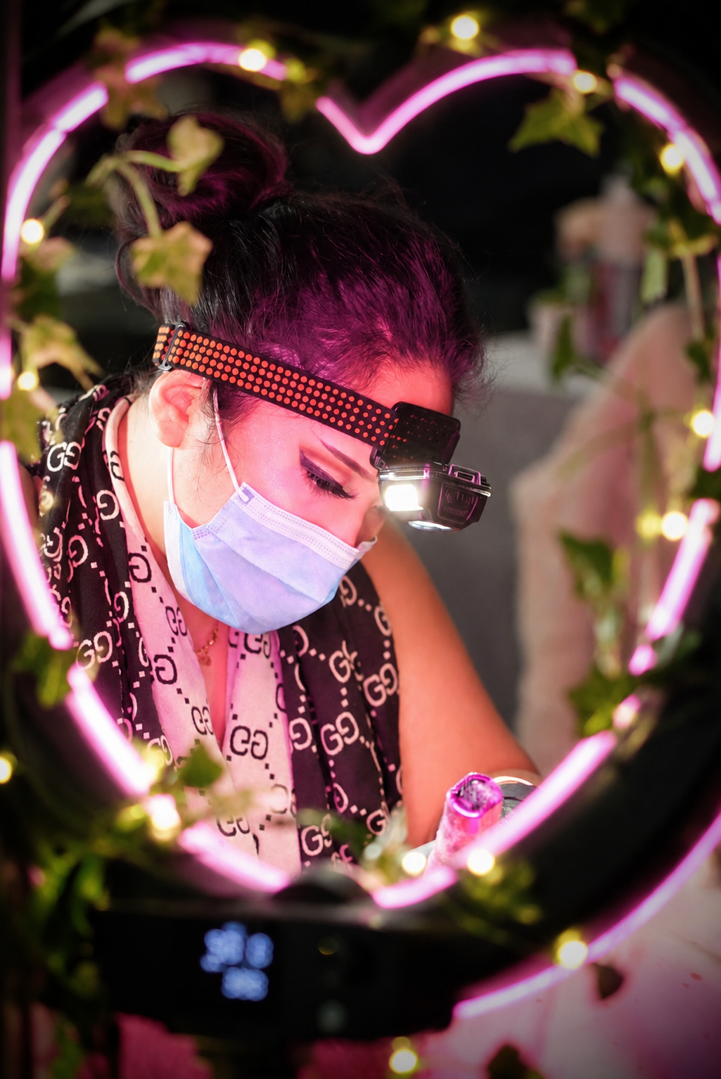 Shira at work, framed by a pink heart-shaped studio light
