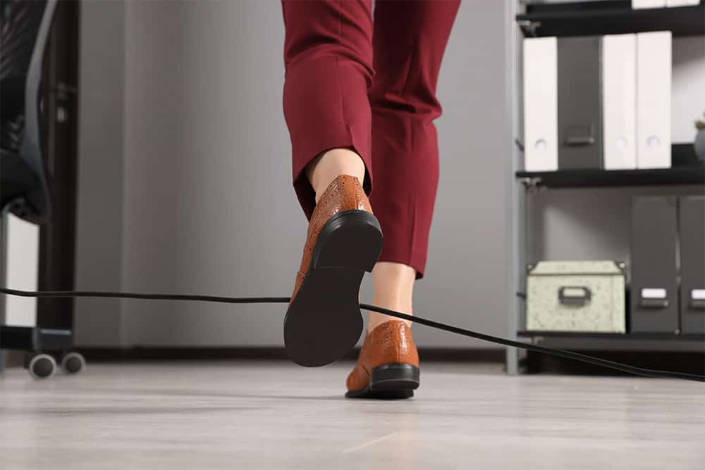 A person who is almost tripping on a wire in the office A person who is almost tripping on a wire in the office