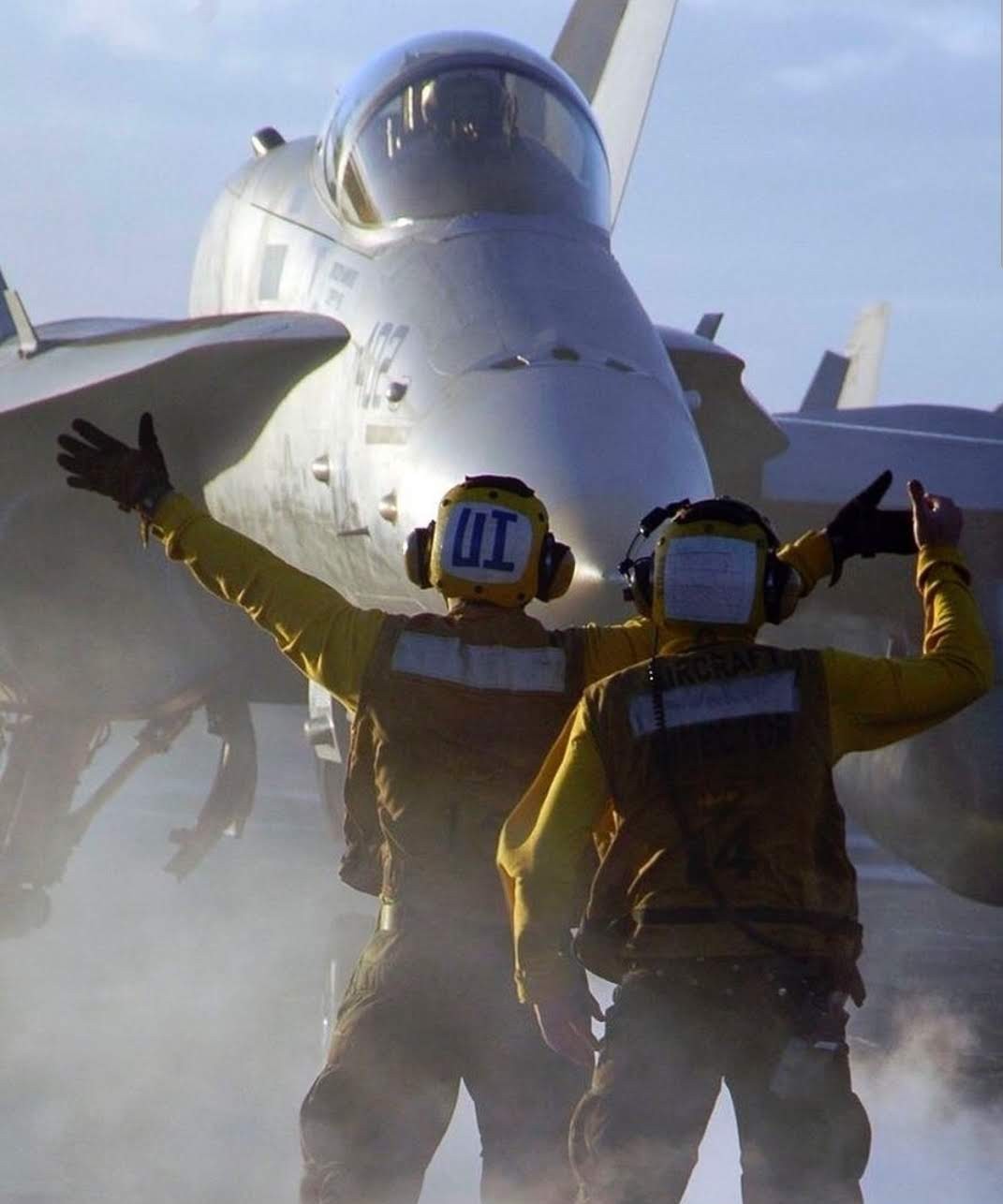Flight deck directors guiding an F/A-18 toward the catapult