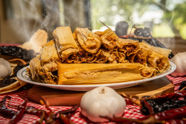 A plate full of steaming tamales on a decorated table.