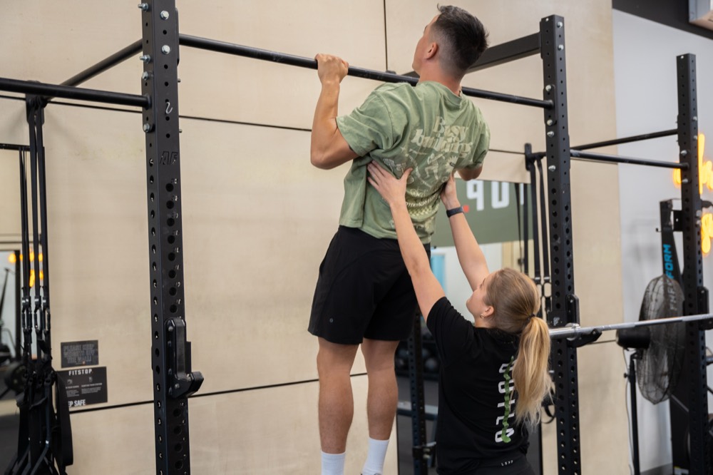 Coach spotting a client during an assisted pull-up