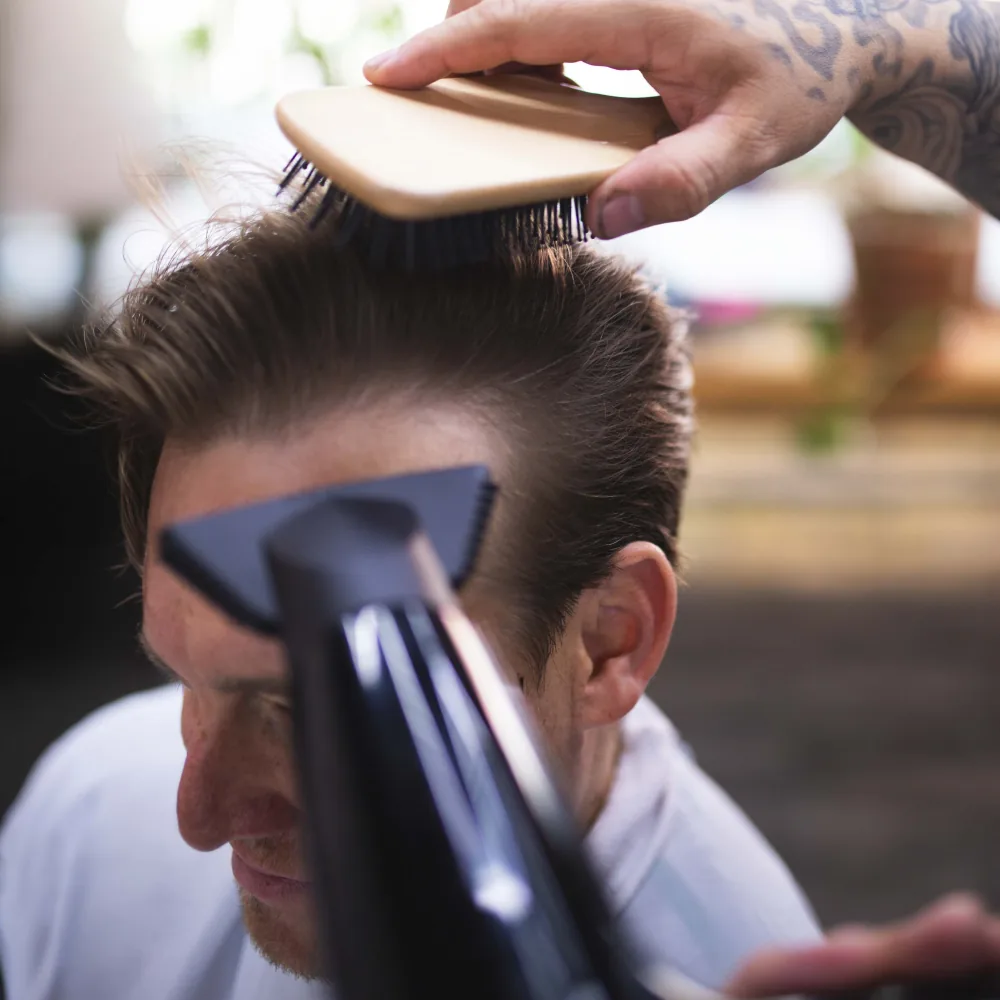 Studio AZ barber blow-drying and styling a men's slick back haircut in Minneapolis