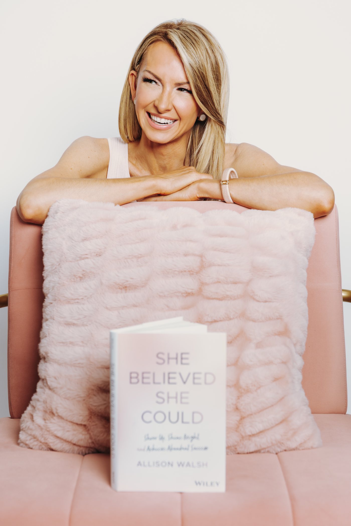 Allison Walsh laughing, leaning on a blush chair