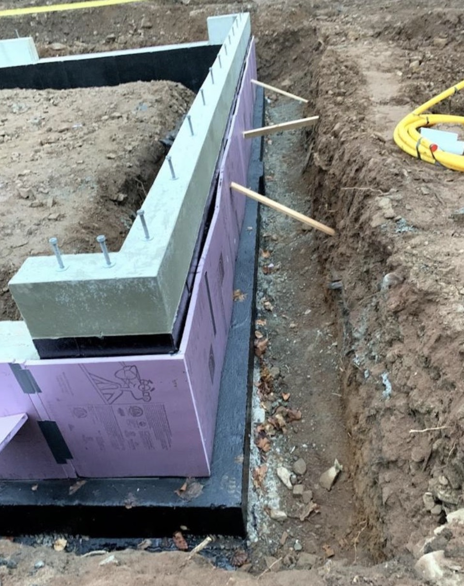Foundation footing drain installation carrying groundwater away from a foundation wall