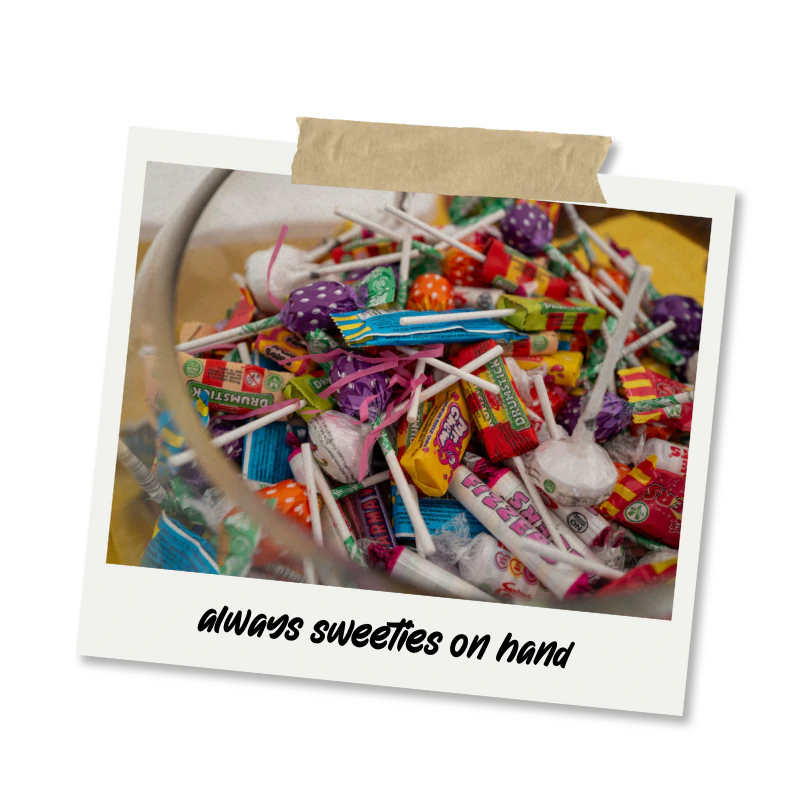 A clear glass bowl filled with various candies, including lollipops and wrapped sweets, with a caption that says 'always sweeties on hand'.