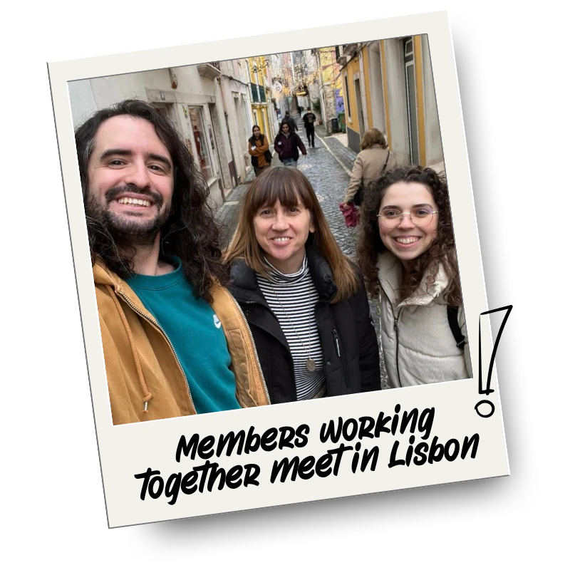 Three people standing on a cobblestone street in Lisbon, Portugal, smiling at the camera. The street is lined with colourful buildings and other pedestrians pass by.