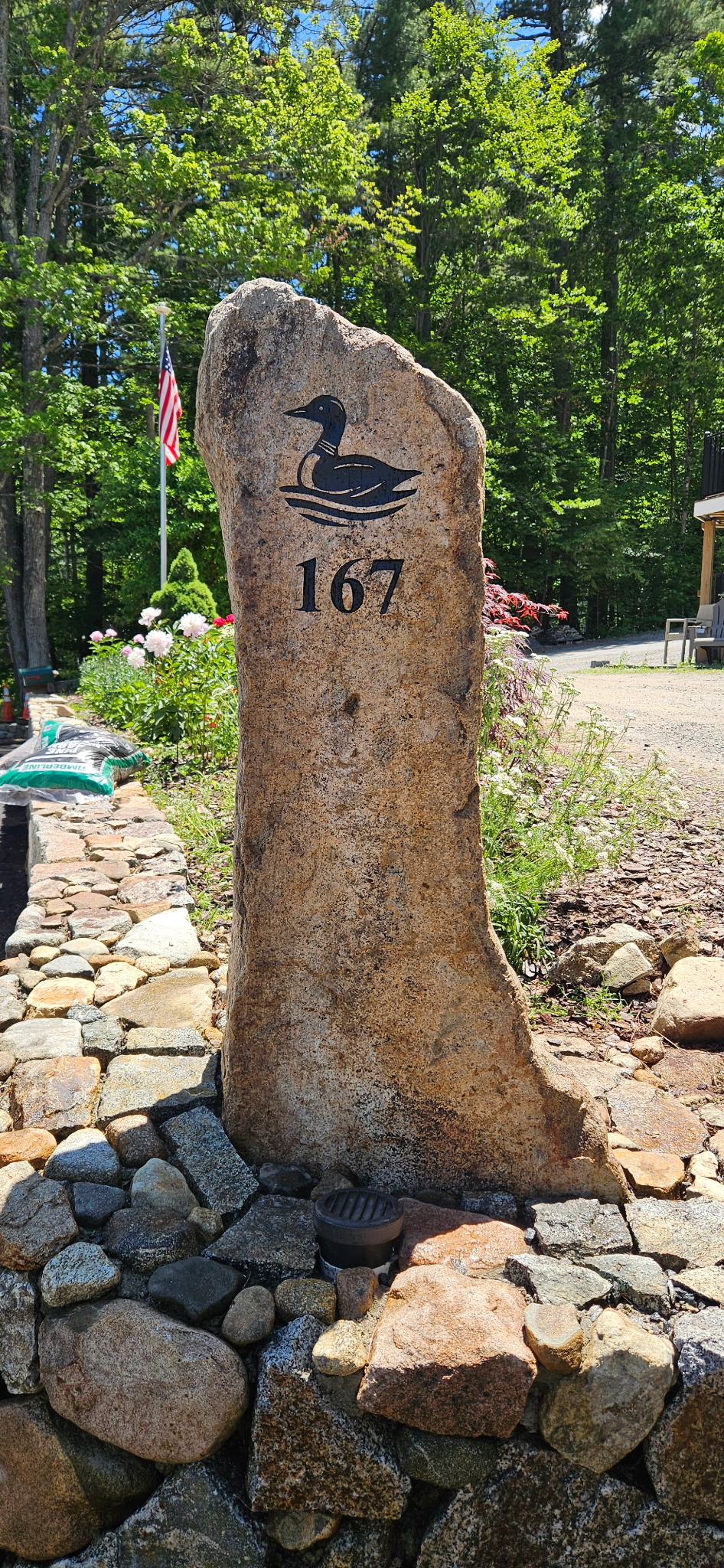 Loon artwork and house number 167 on a granite post