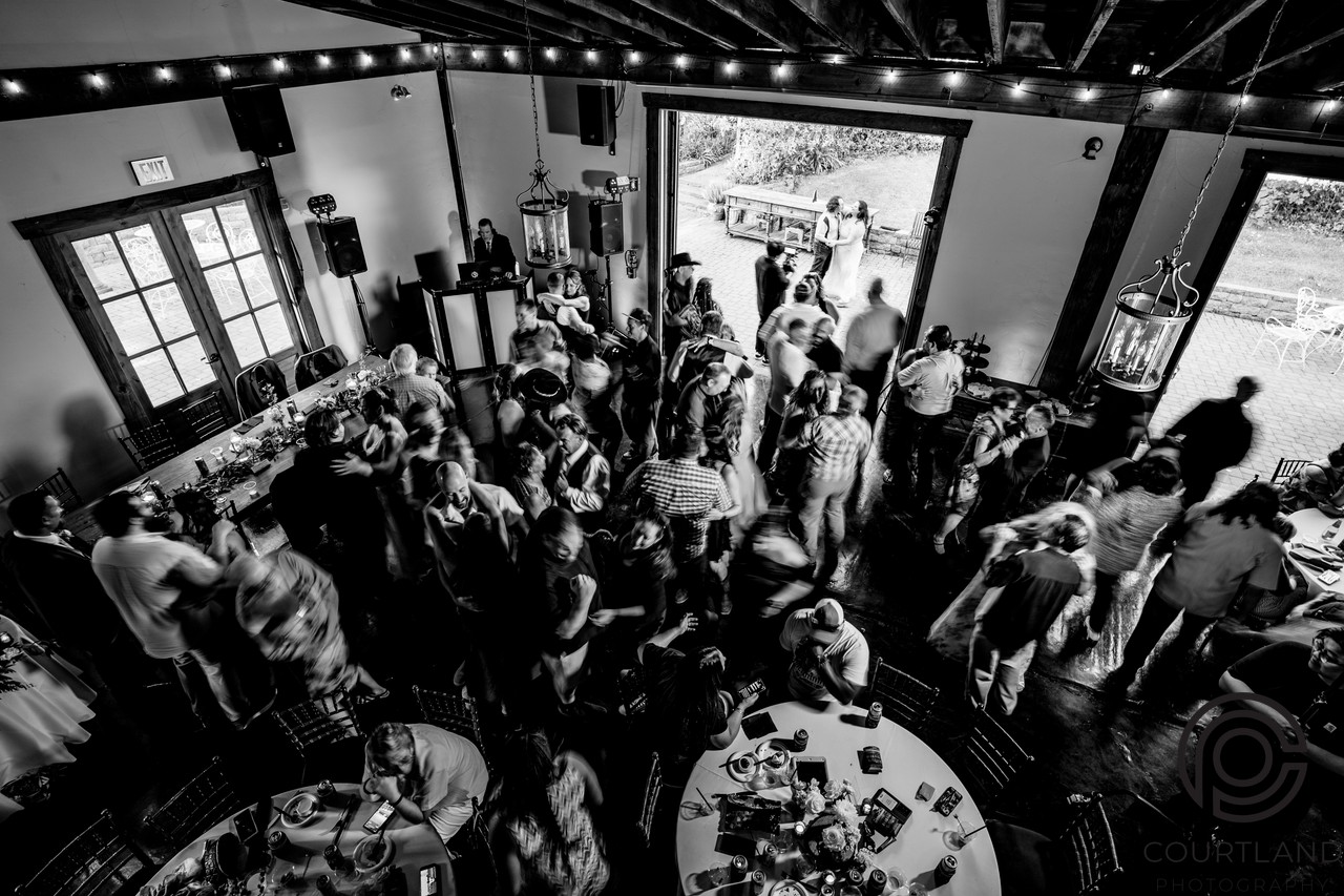Wedding guests dancing at a Sacramento reception with the DJ booth in view
