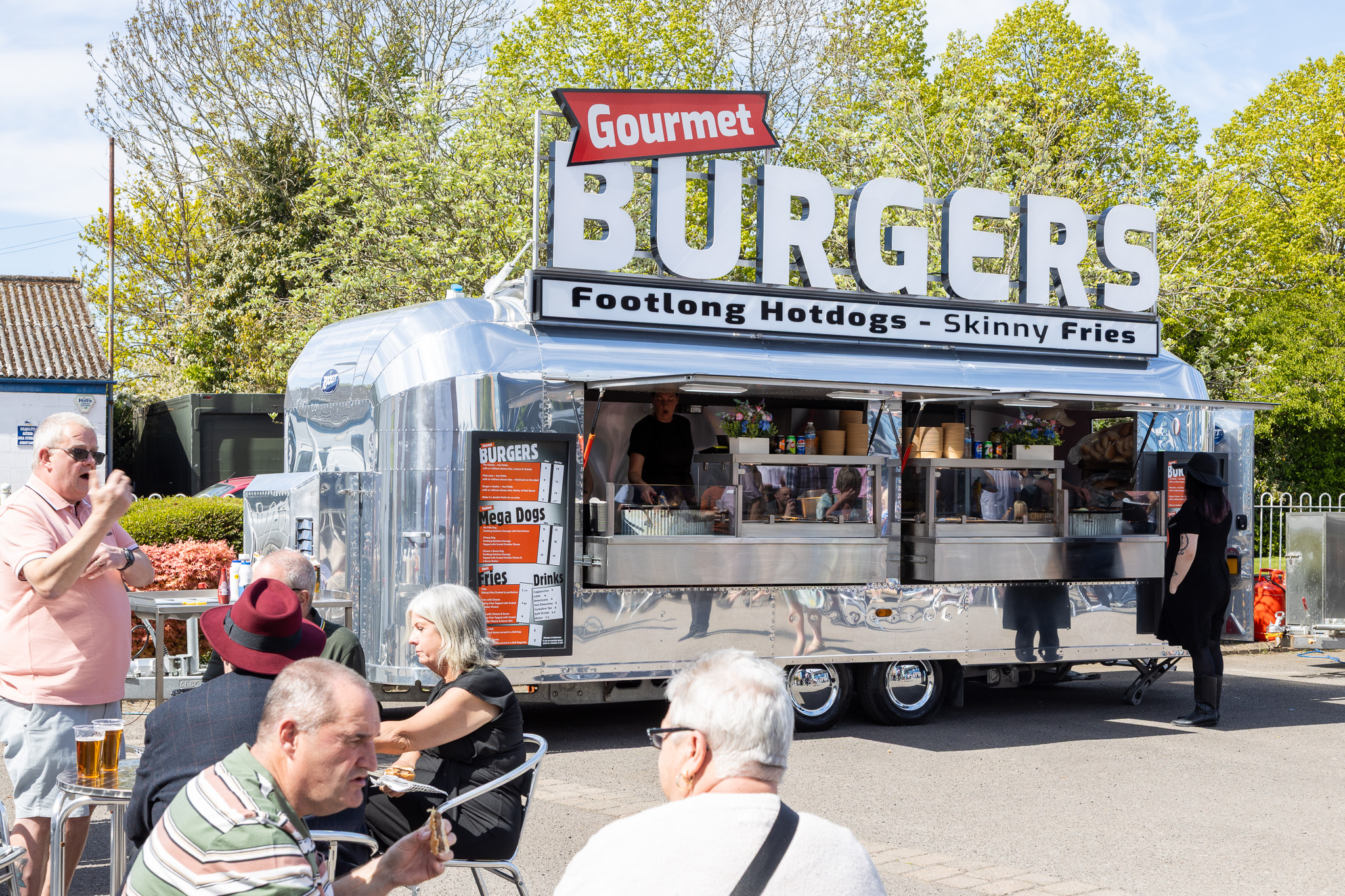 A professional mobile catering trailer at a high-volume outdoor festival, showcasing efficient crowd management and natural lighting.