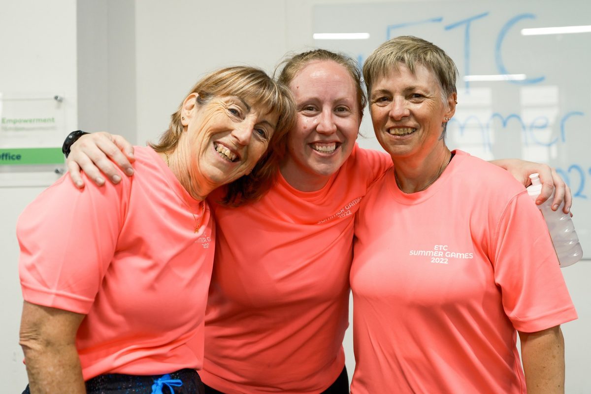 Three members arm in arm laughing