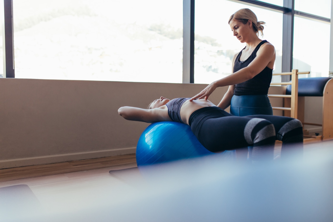 Physiotherapist guiding a rehab exercise on a stability ball